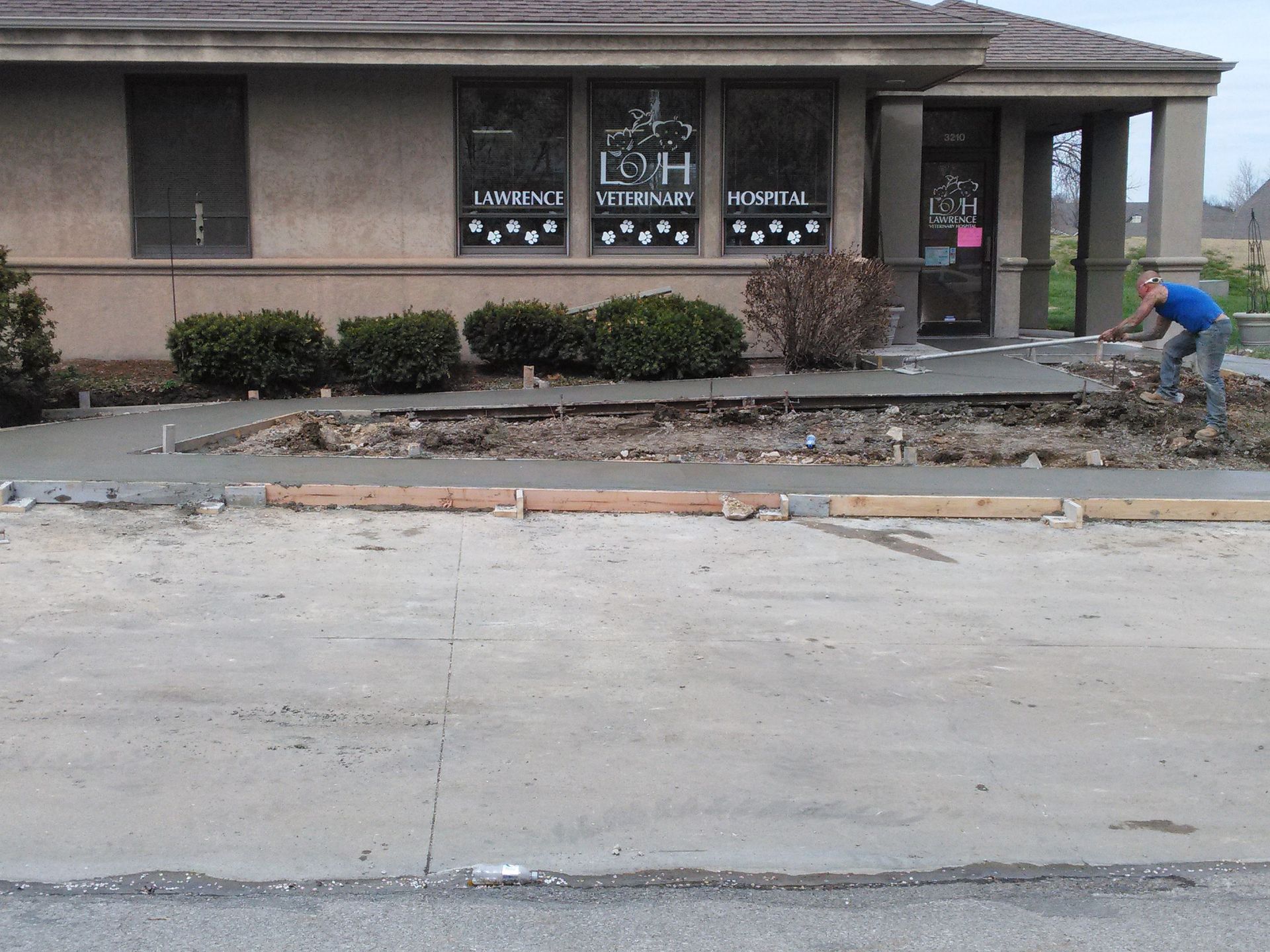 A concrete driveway is being built in front of a building that says leigh