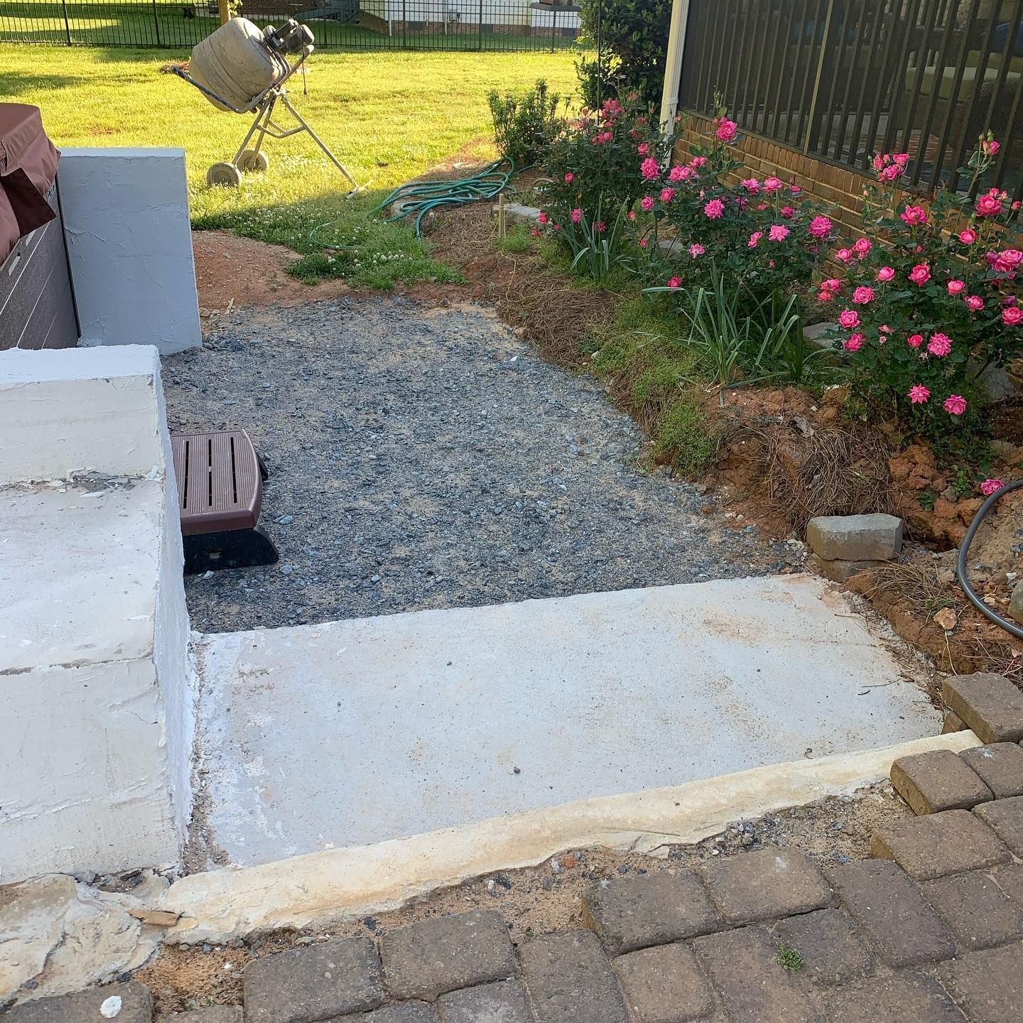 Concrete and gravel pathway with step, adjacent to a garden with pink flowers.