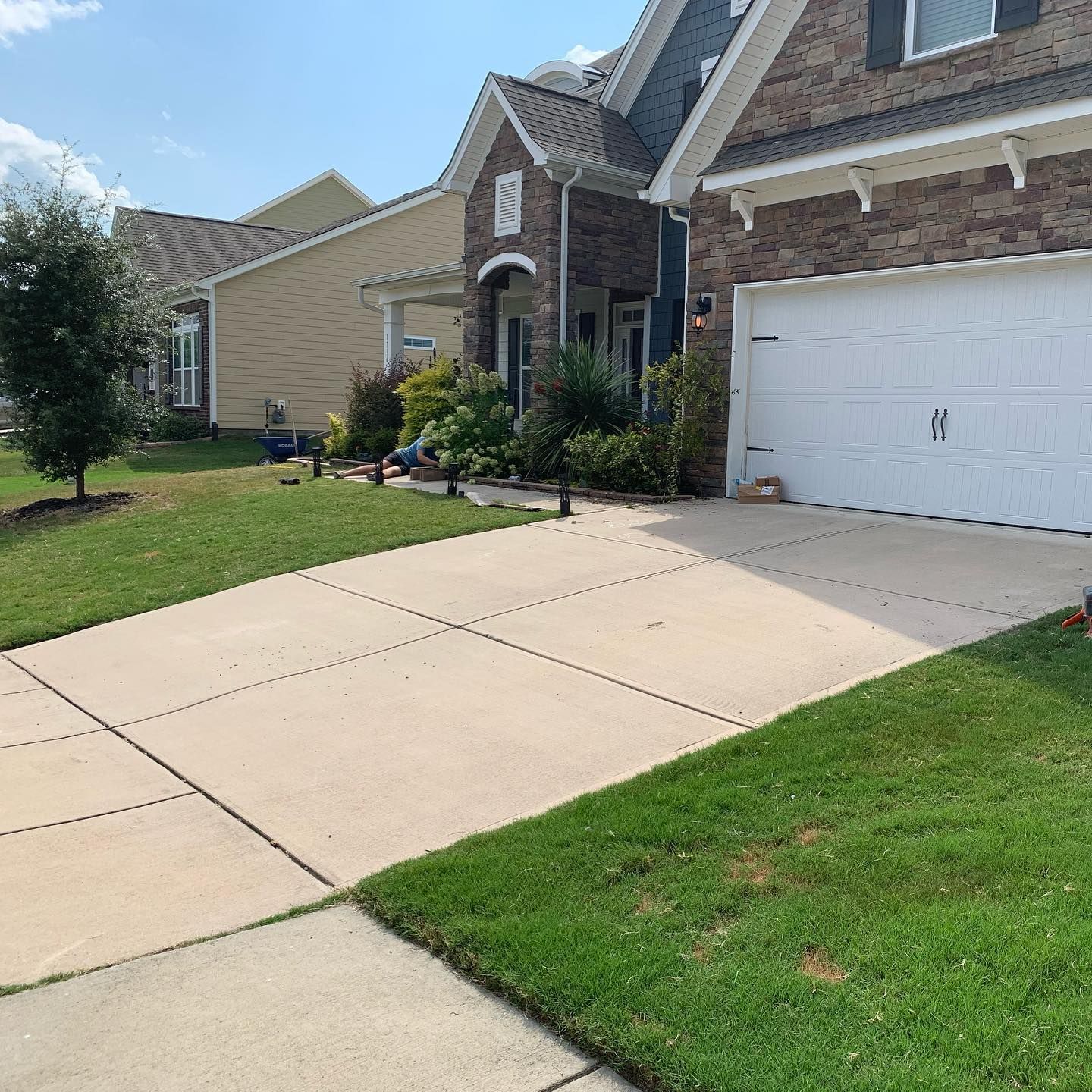 Driveway leading to a house with a garage. Green grass and blue sky visible.
