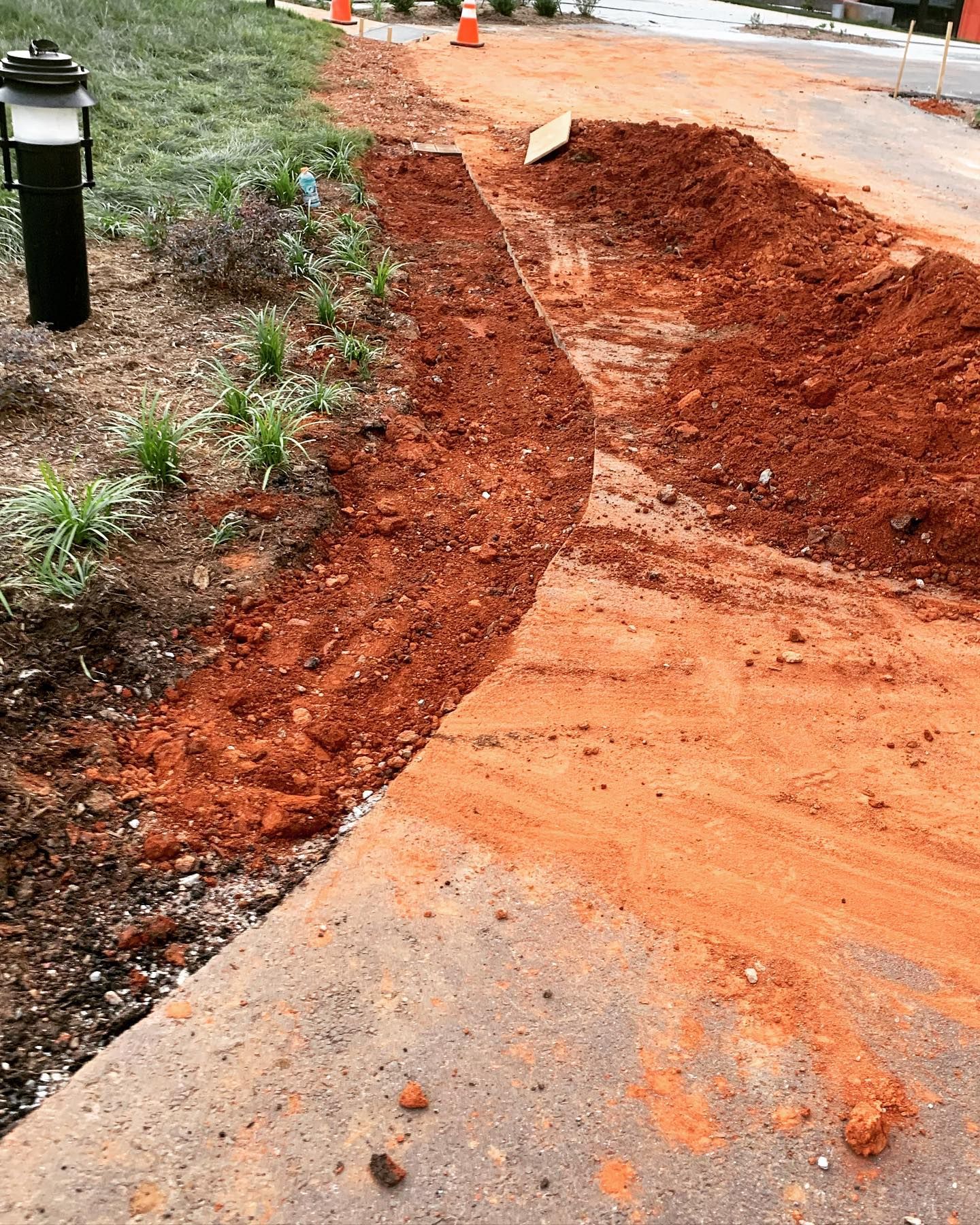 Sidewalk under construction; trench dug in red clay alongside the path.