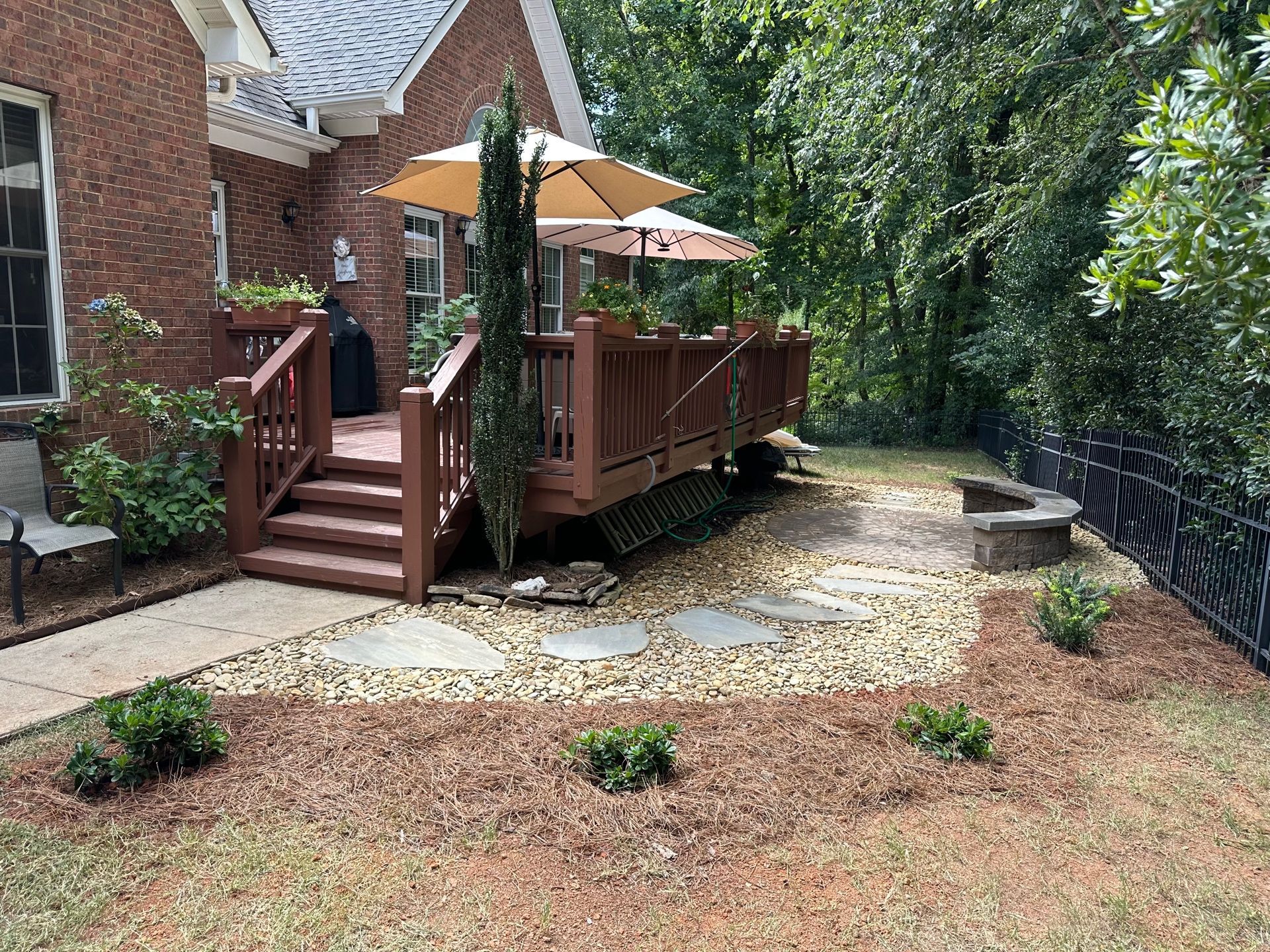 Red brick house with a wooden deck, patio, and a fire pit.