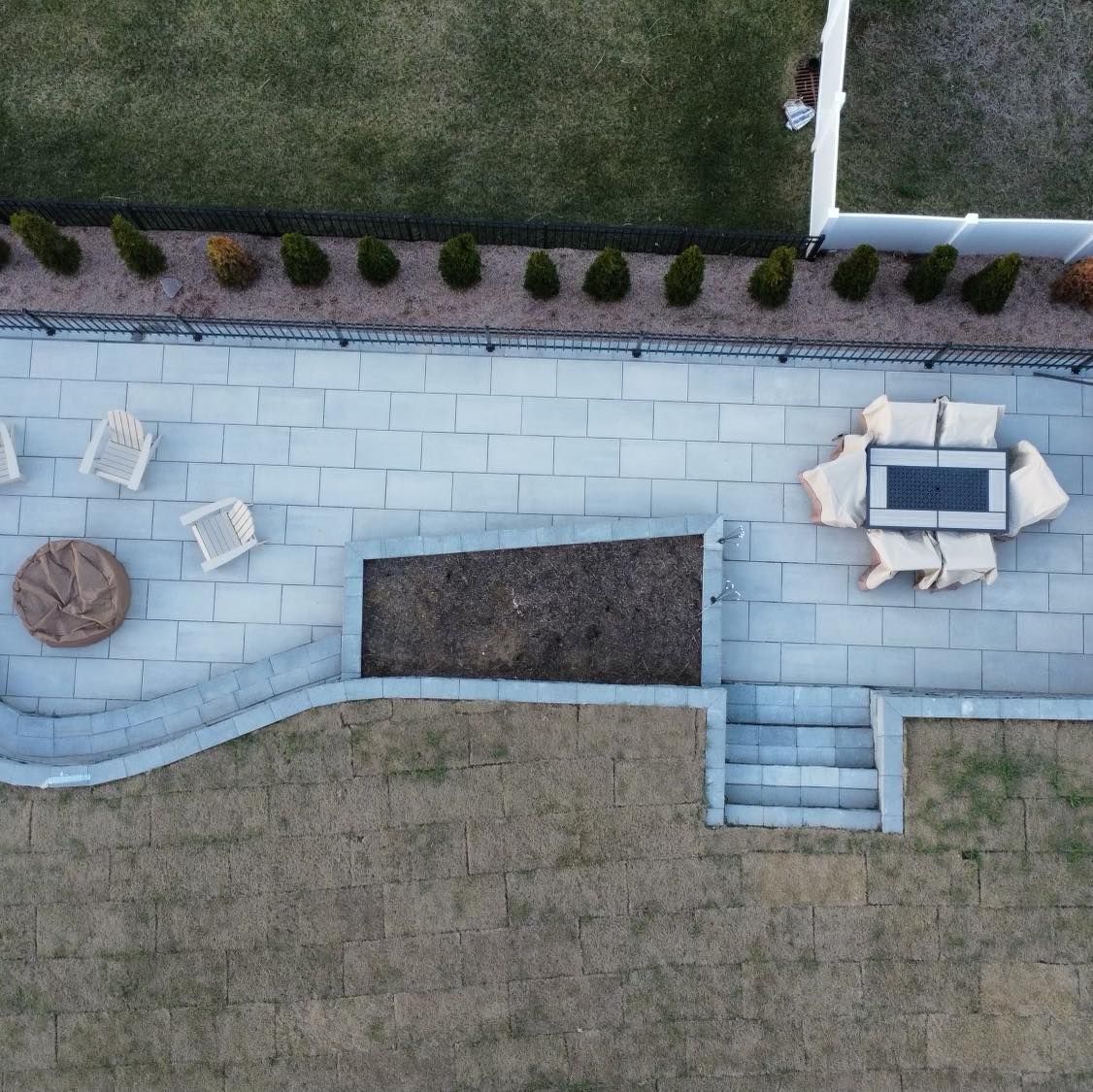 Overhead view of a patio with stone pavers, outdoor furniture, and landscaping.