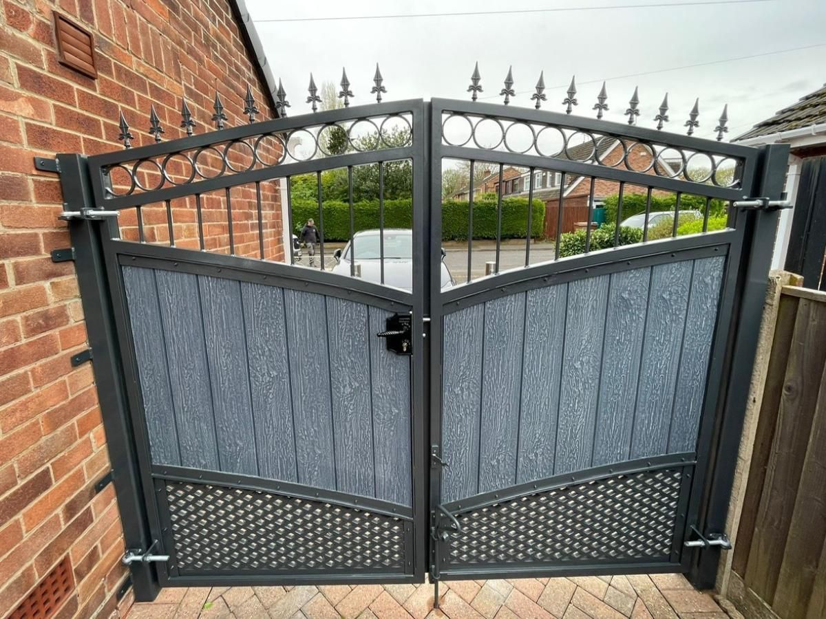 Arched silver grey composite gates with decorative metalworks above and below 