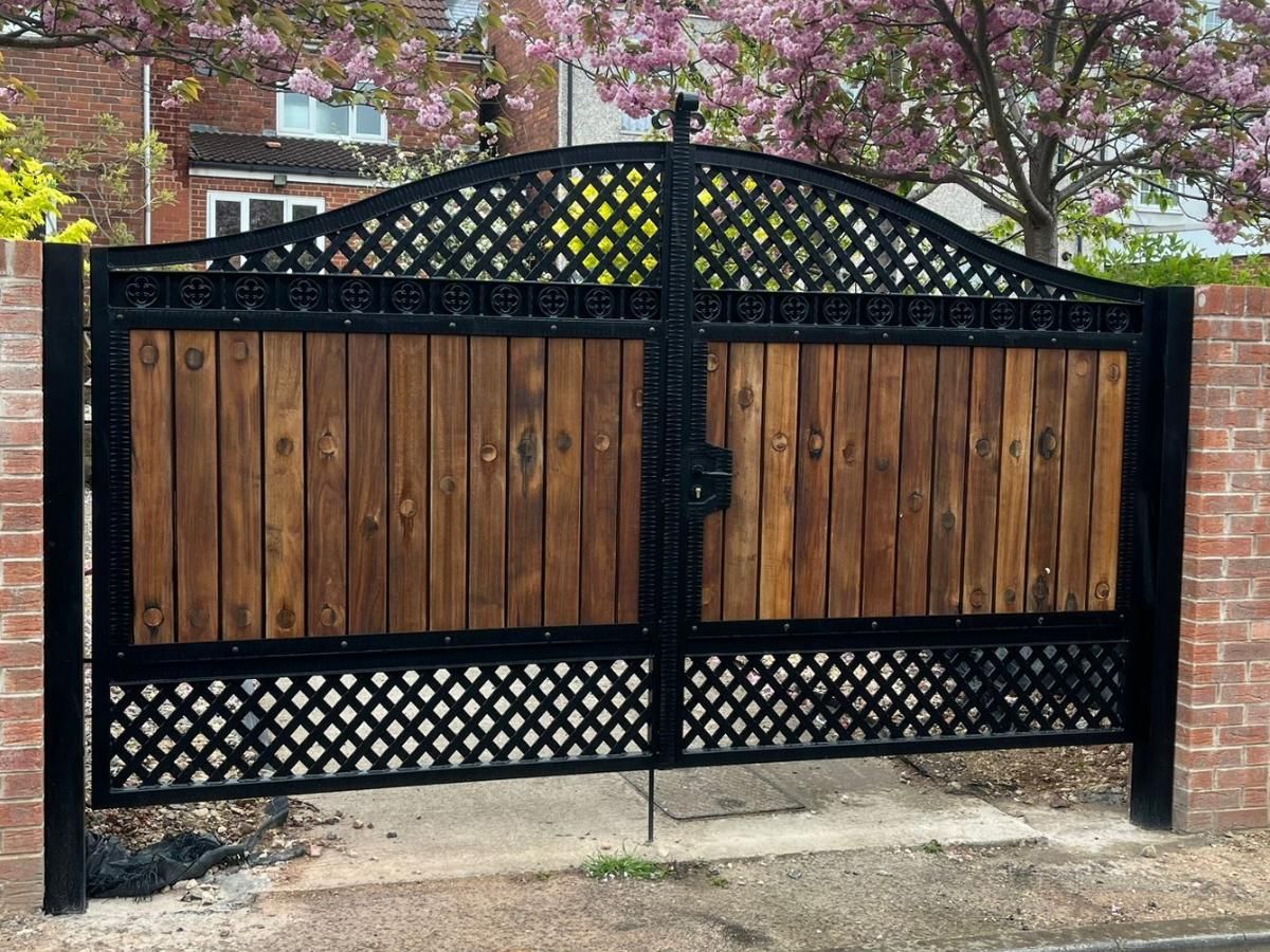 Arched metal gates with metalworks above and below with wooden boards