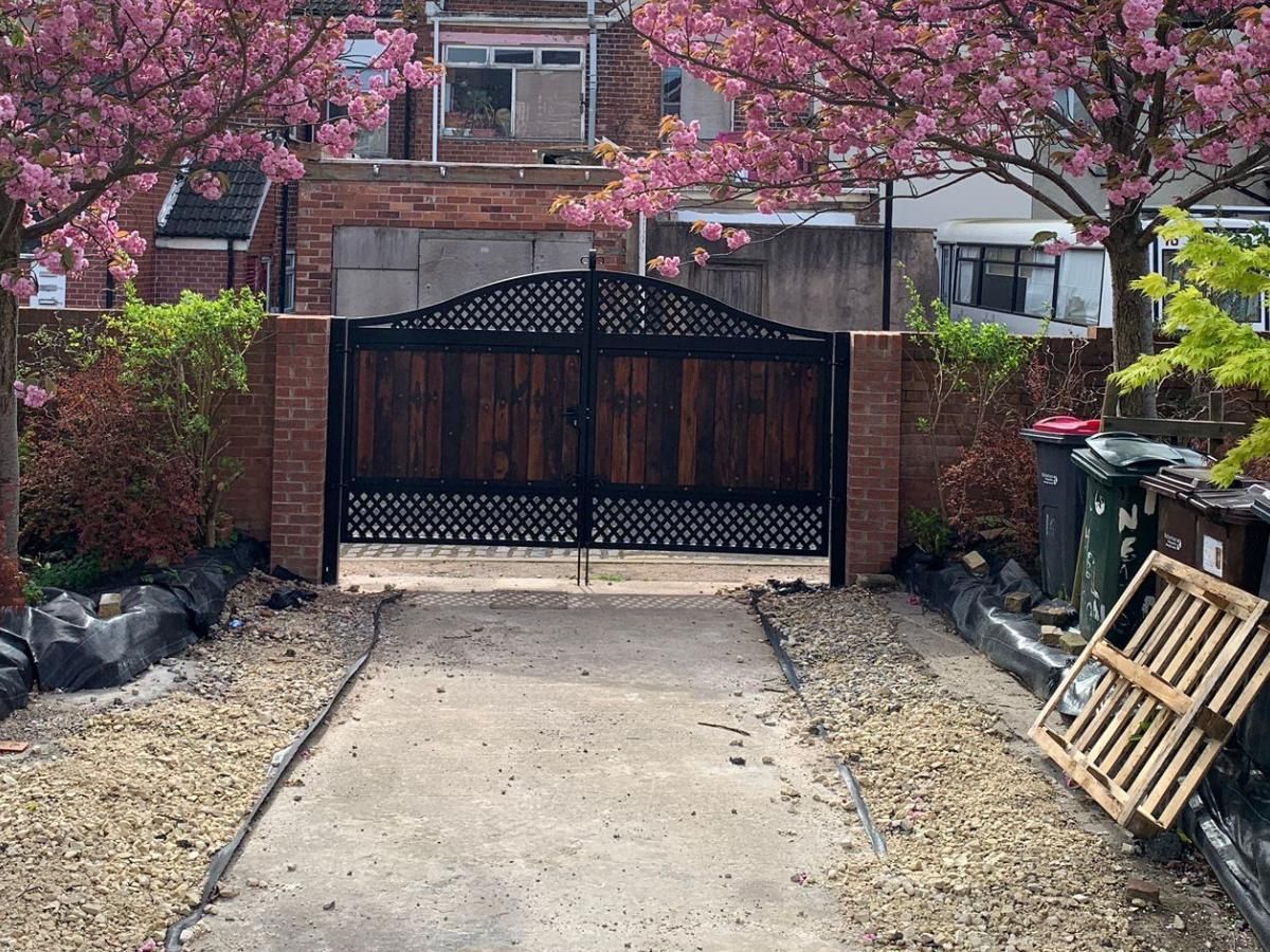 Arched metal gates with metalworks above and below with wooden boards