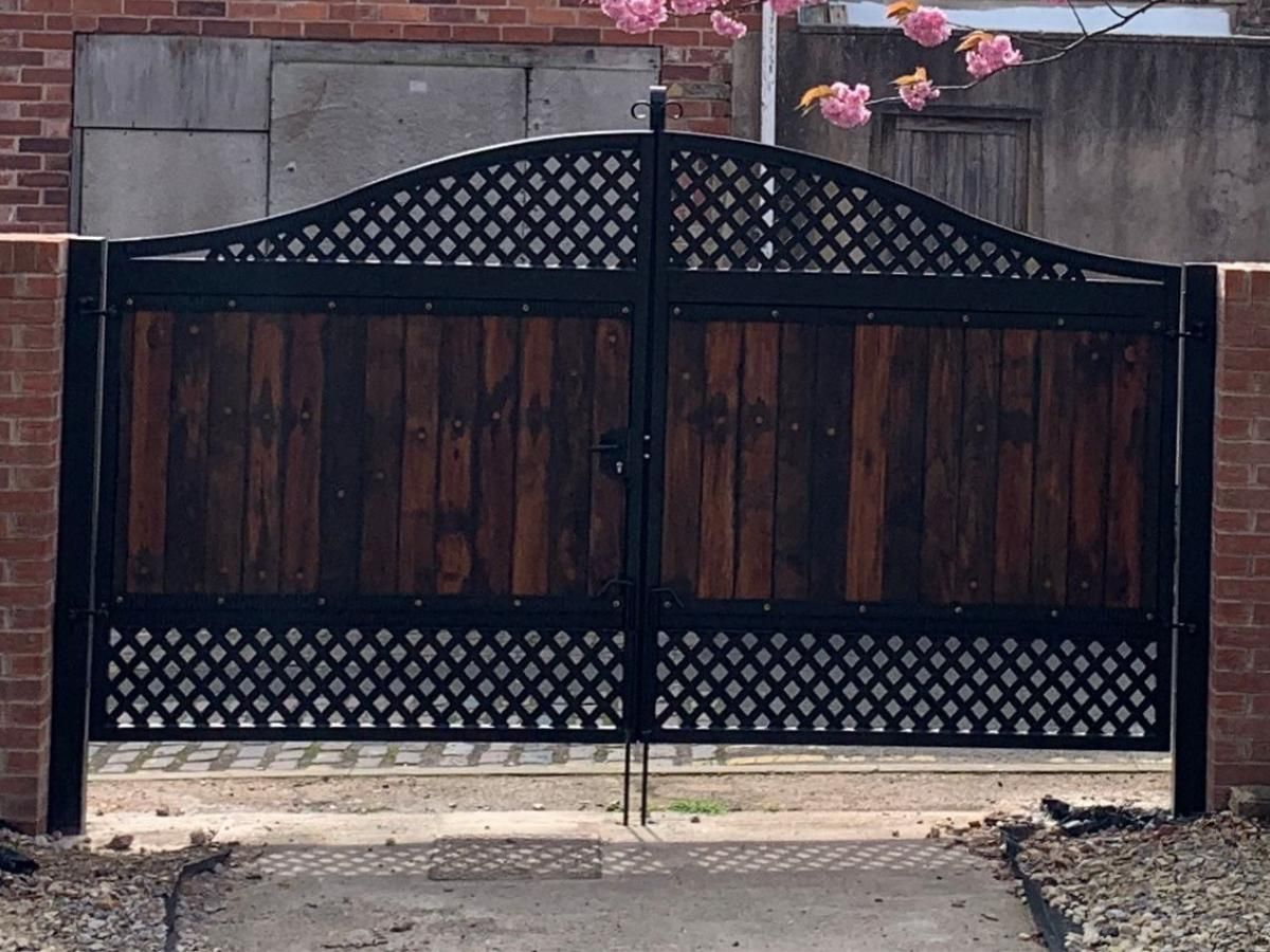 Arched metal gates with metalworks above and below with wooden boards