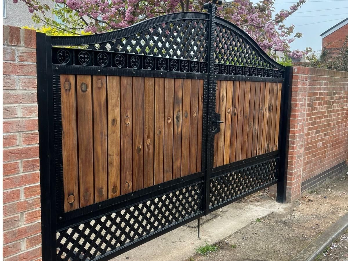 Arched metal gates with metalworks above and below with wooden boards