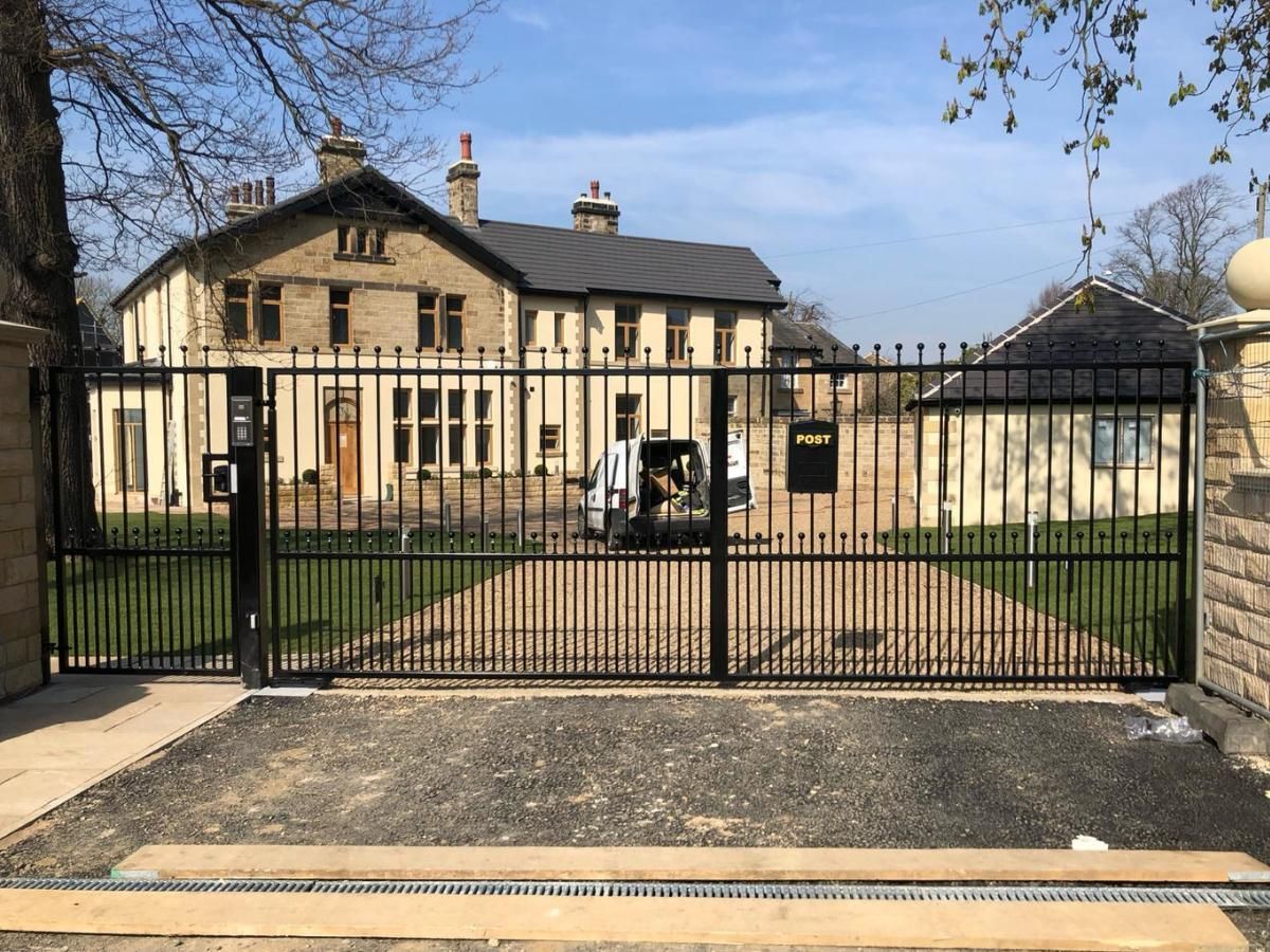 Arched silver grey composite gates with metalworks above and below with additional stainless steel handles 