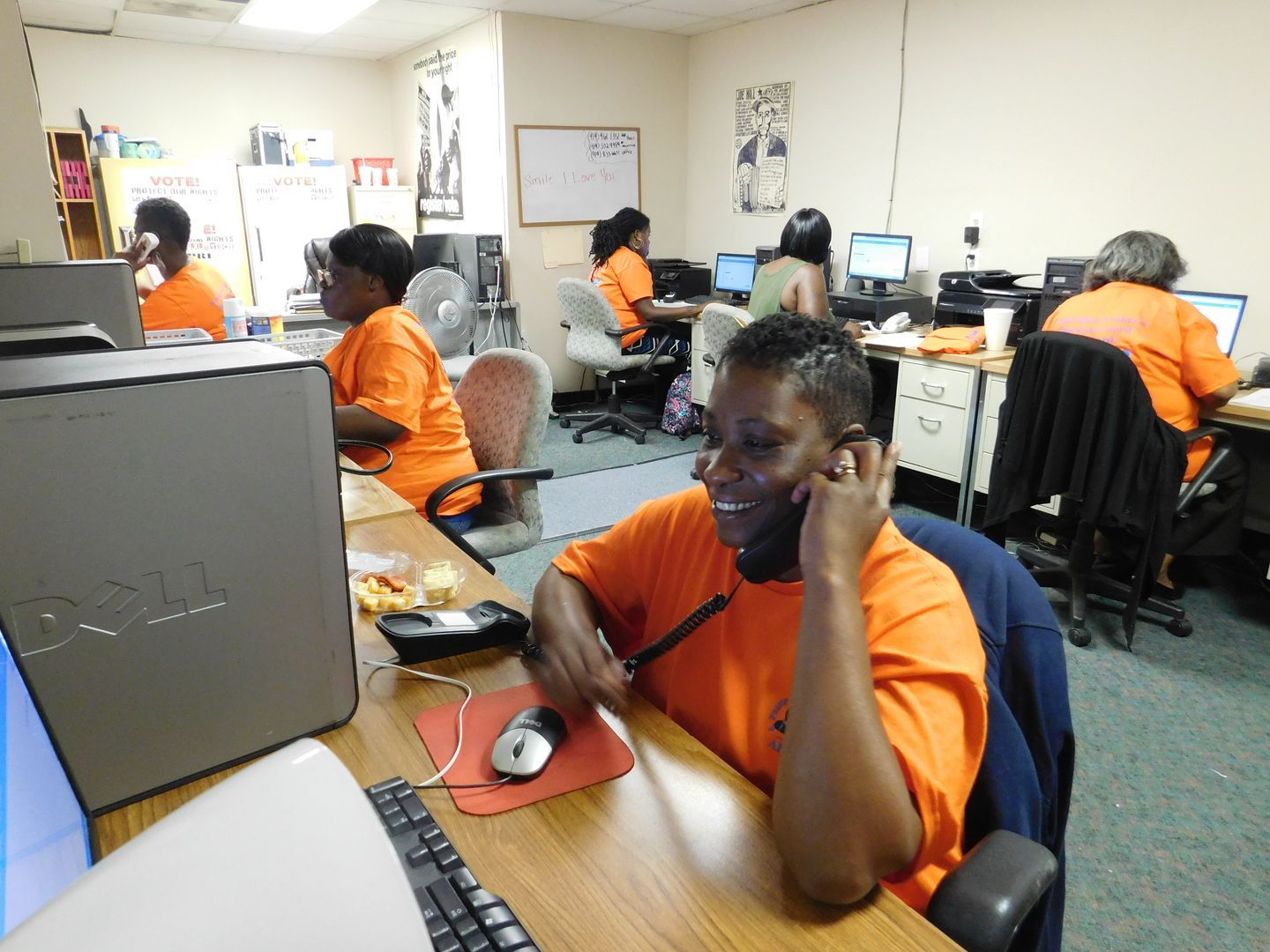 A Get Out The Vote volunteer woman in an orange shirt is talking on a phone