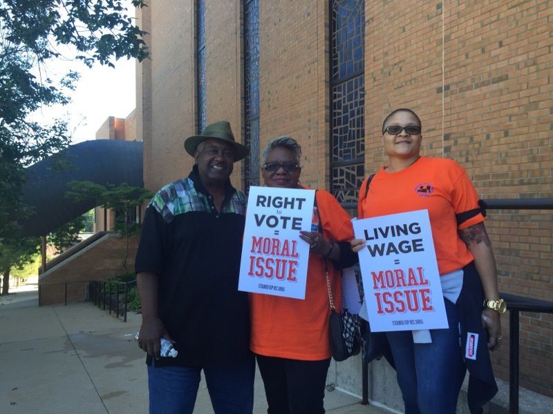 Three people holding signs that say right vote moral issue and living wage moral issue