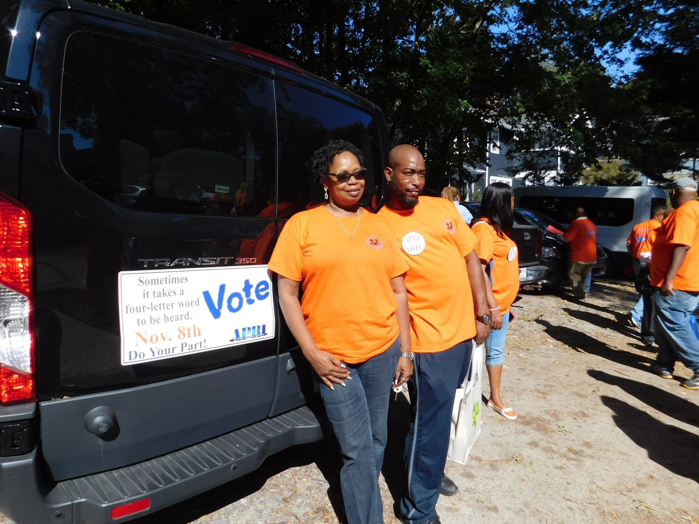 A man and a woman standing in front of a van that says vote
