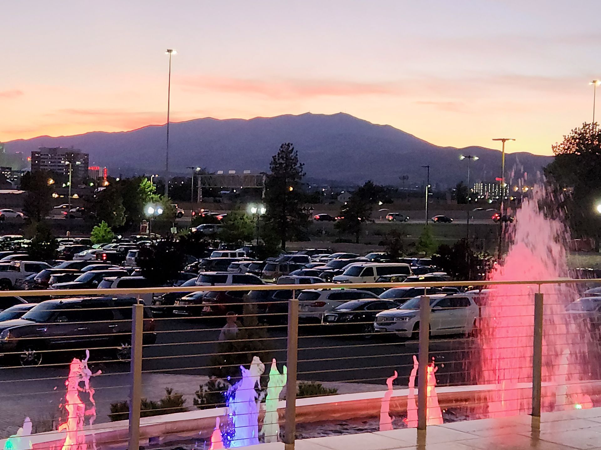 A fountain in a parking lot with mountains in the background