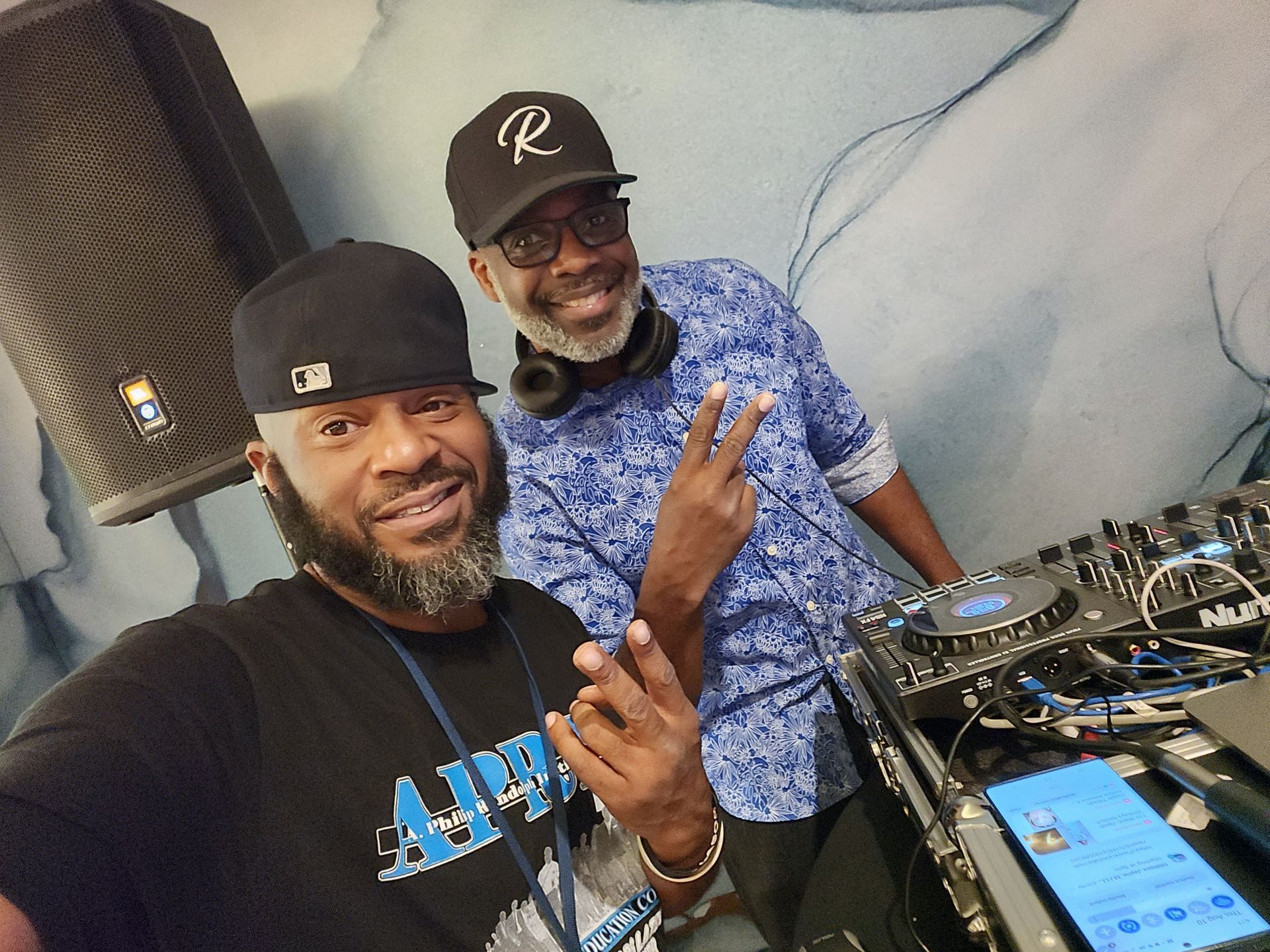 Al Brown posing for a picture with a friend, in front of his dj mixer.