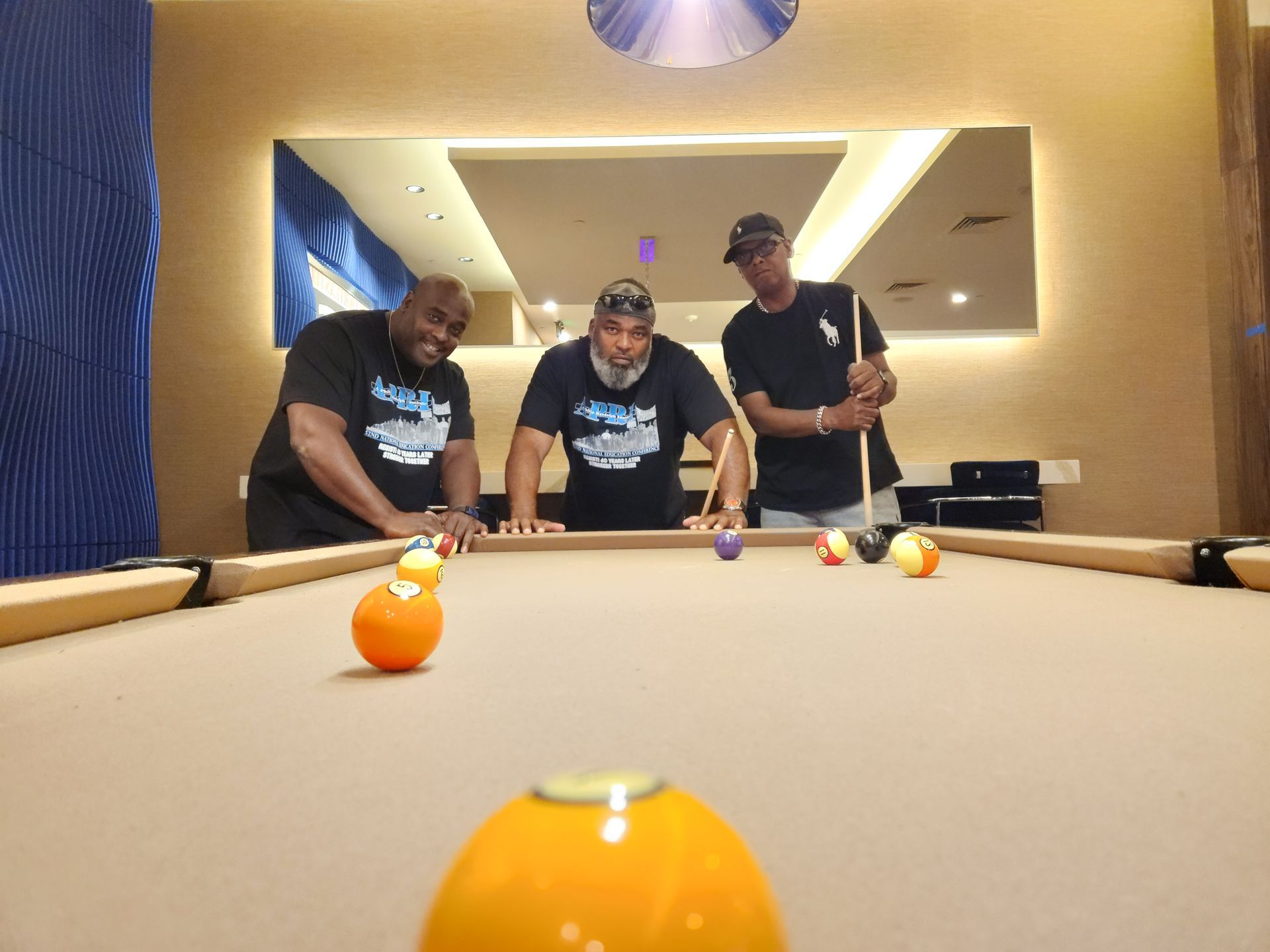 Three men are standing around a pool table playing pool