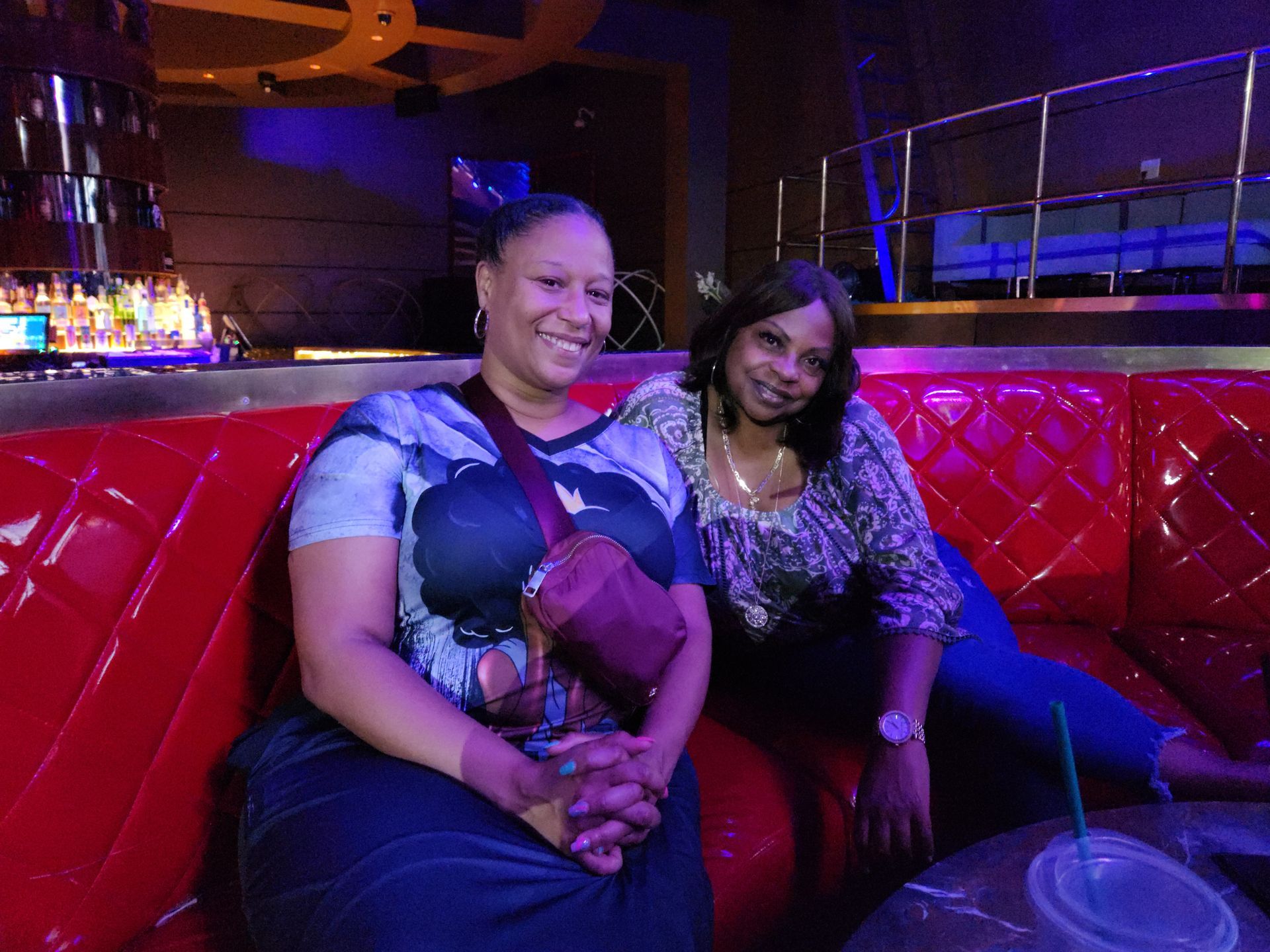 Two women are sitting on a red couch in a dark room  at an APRI 