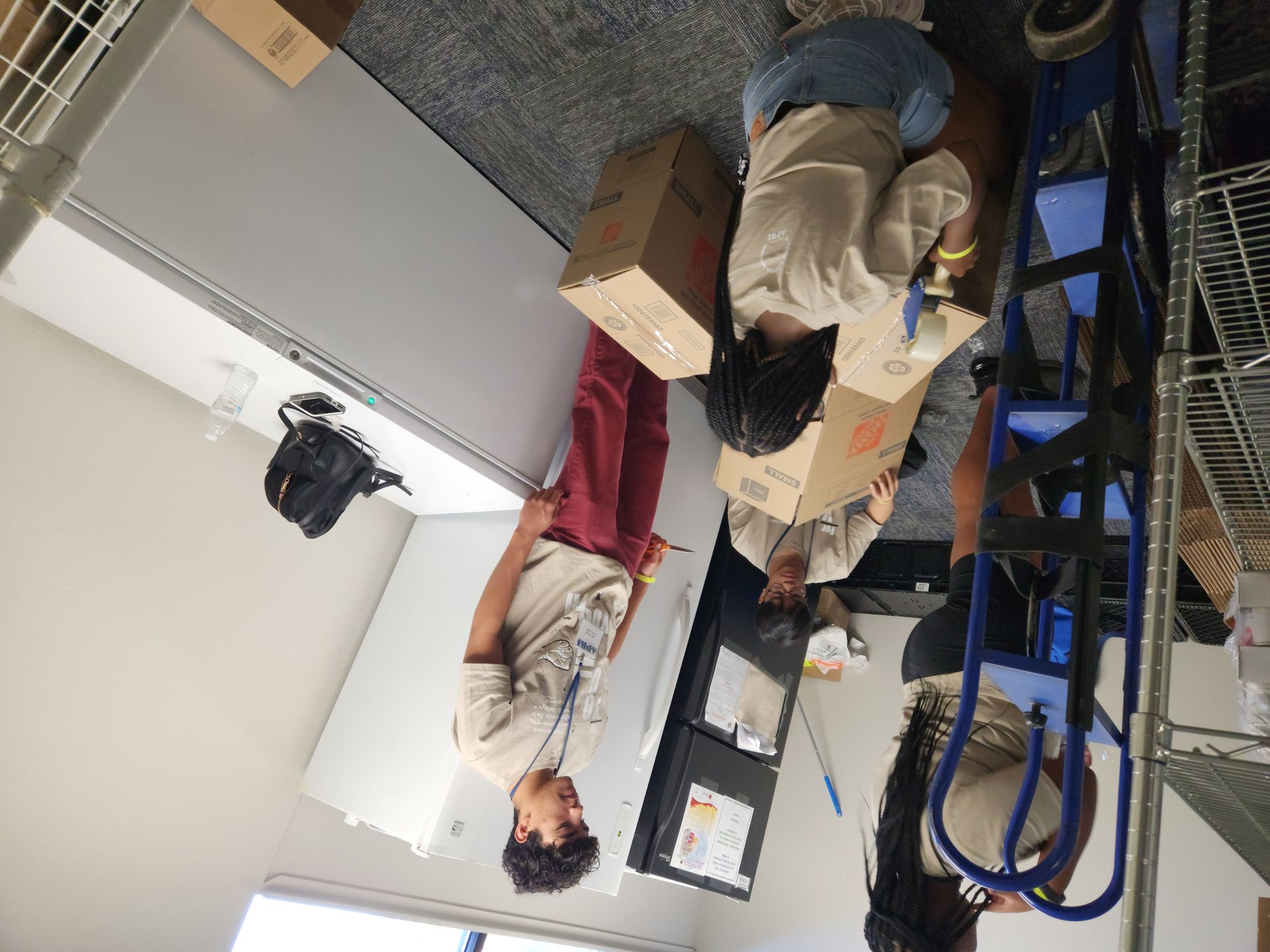 A group of people are sitting around a table holding boxes.