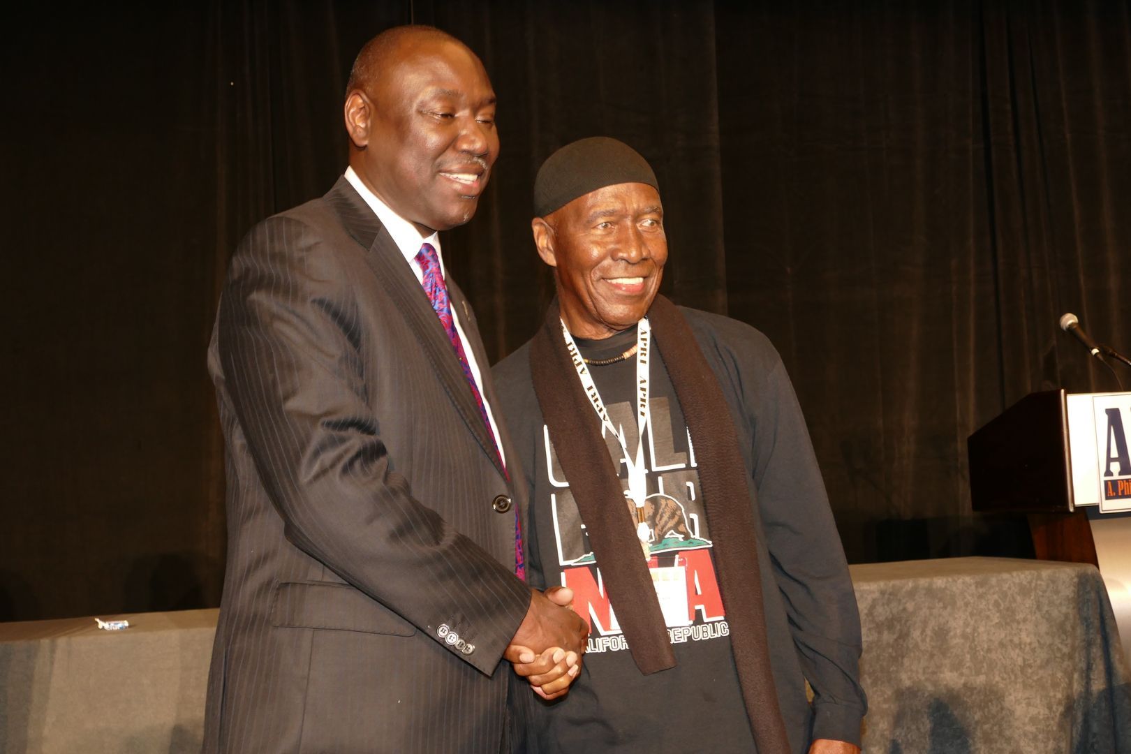 Two men shaking hands in front of a podium at an APRI event