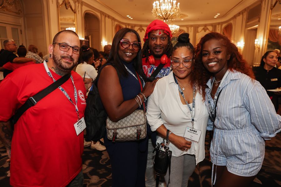 Group of five smiling people posing for a photo indoors.