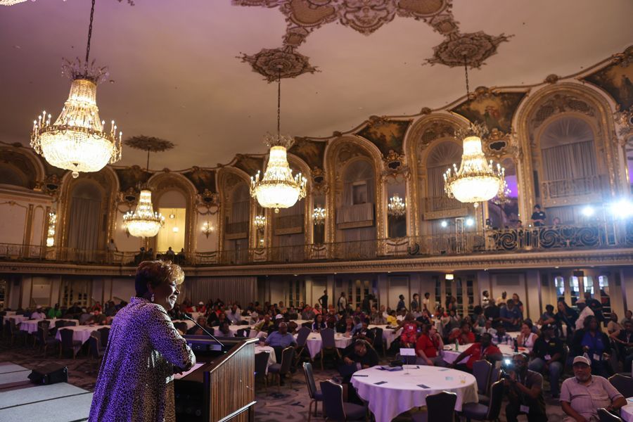 Pres. Brown speaking at podium in ornate ballroom of the Chicago Hilton; crowd seated at tables; chandeliers overhead.