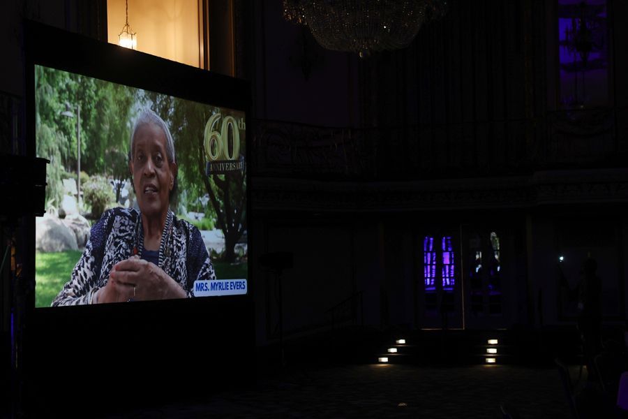 A woman on a screen at a 60th anniversary event.