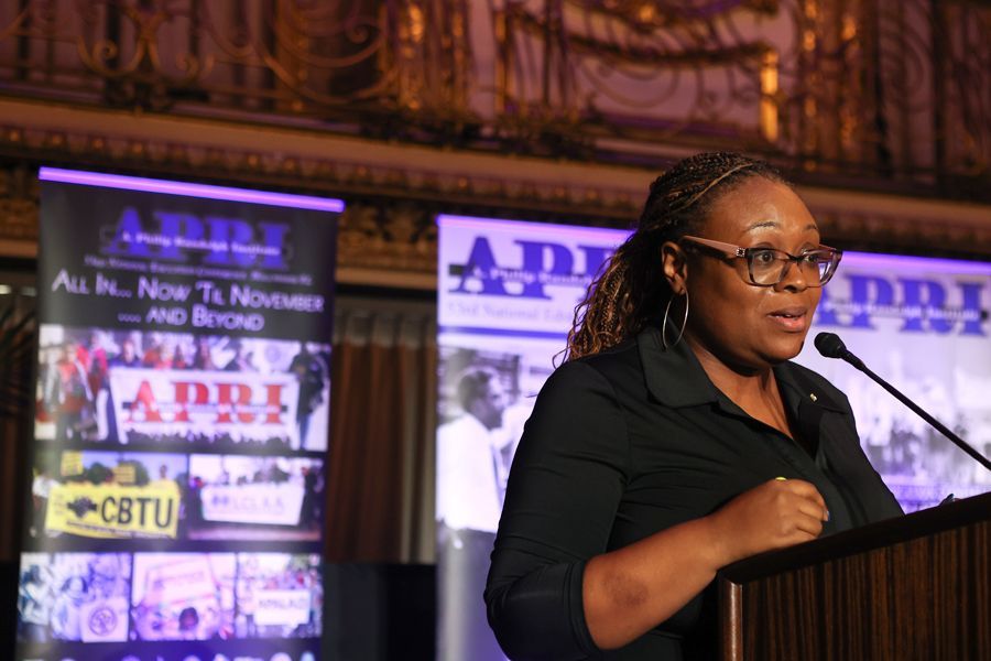 Danielle speaking at a podium with banners that read 