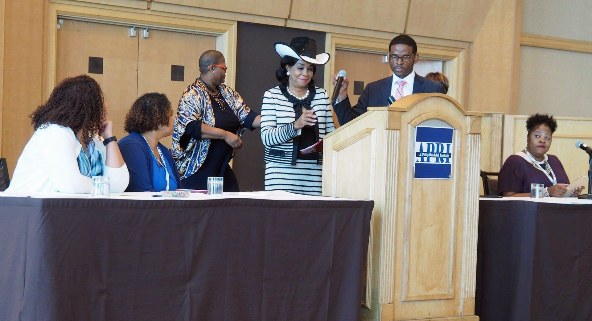 A group of people are sitting at tables in front of a podium.