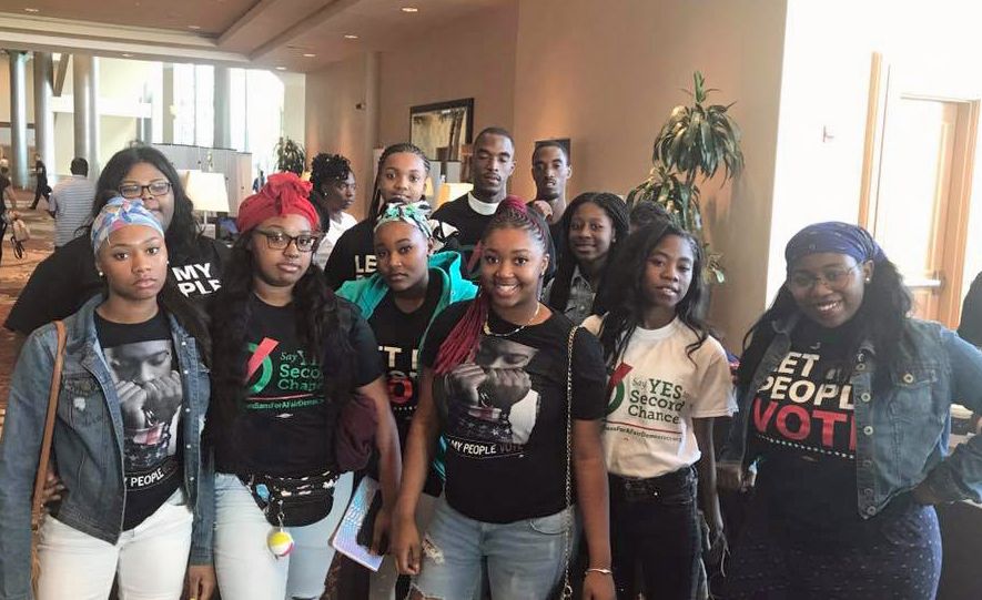 A group of young people are standing next to each other in a room.