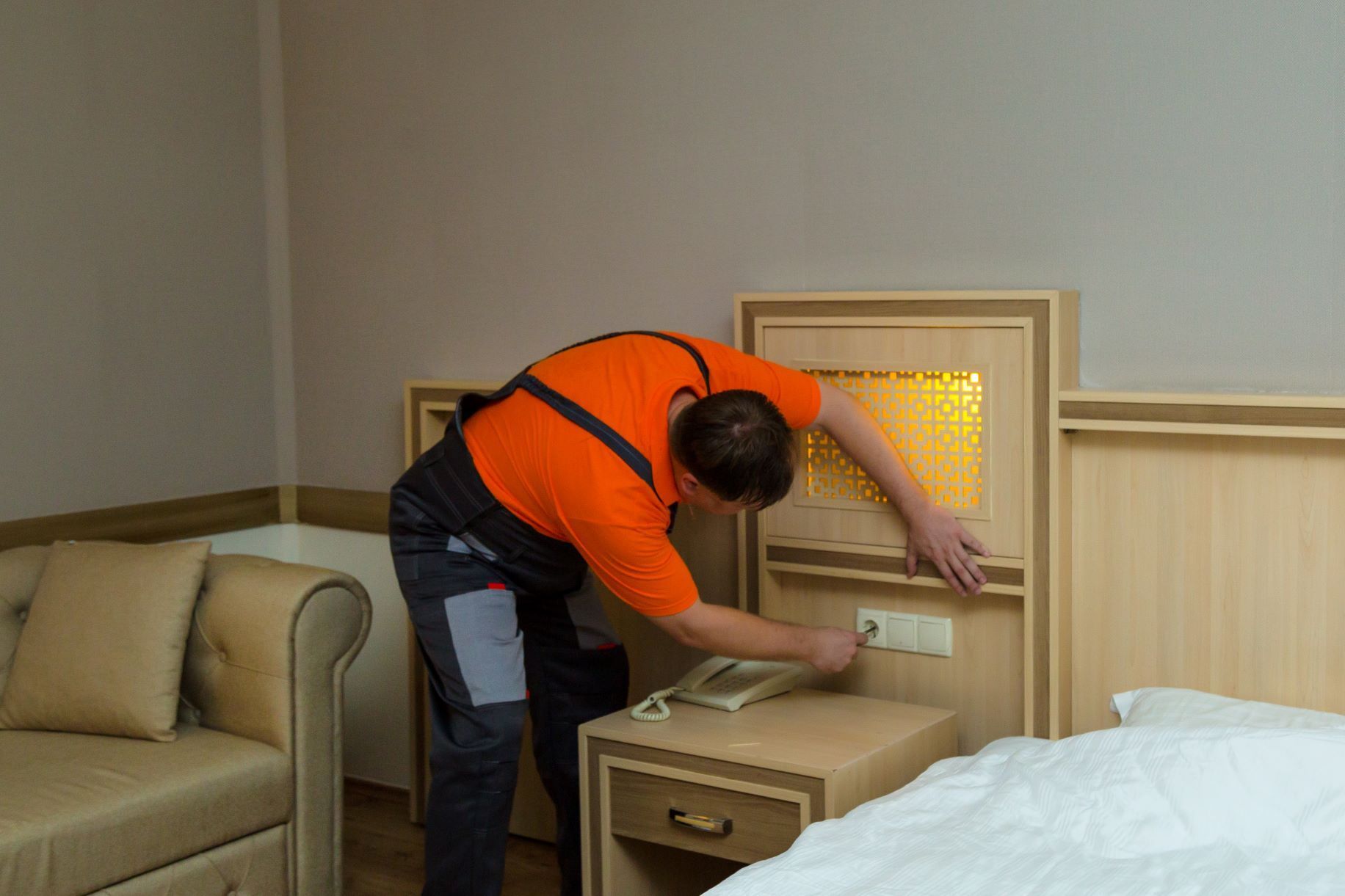 A man is working on a bed in a hotel room.