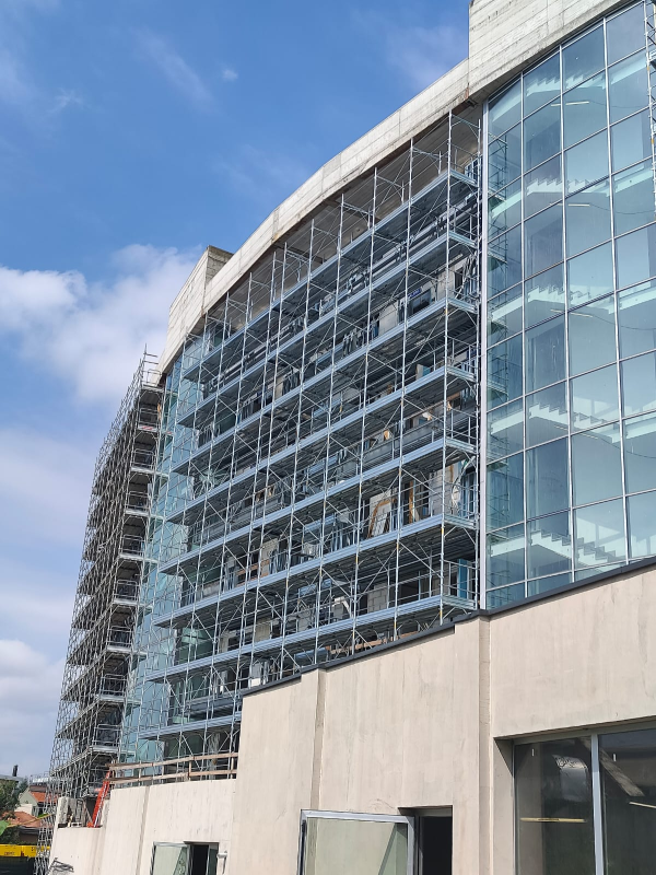 Moderno edificio per uffici in vetro con facciata curva e cielo azzurro limpido.