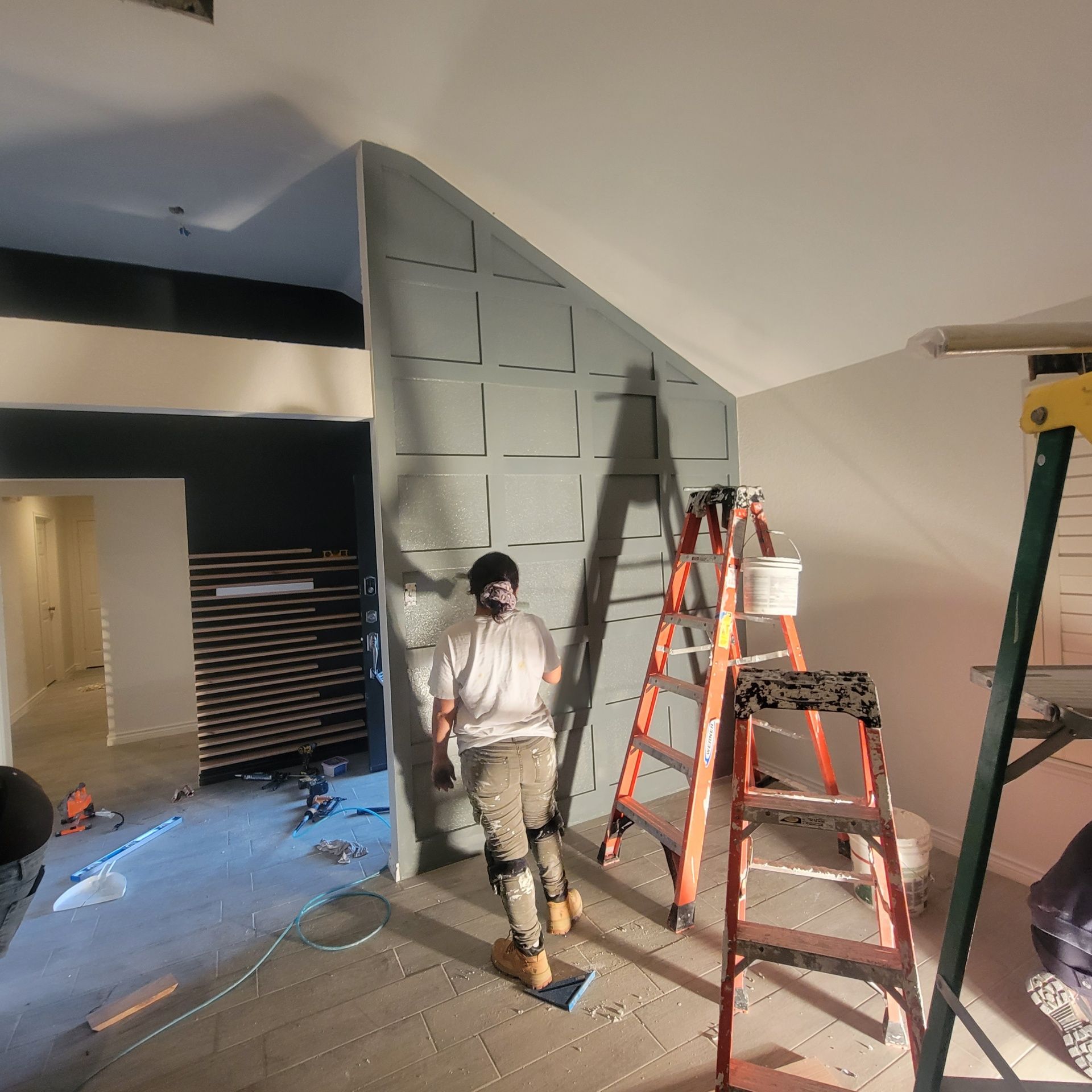 A man is standing next to a ladder in a room.