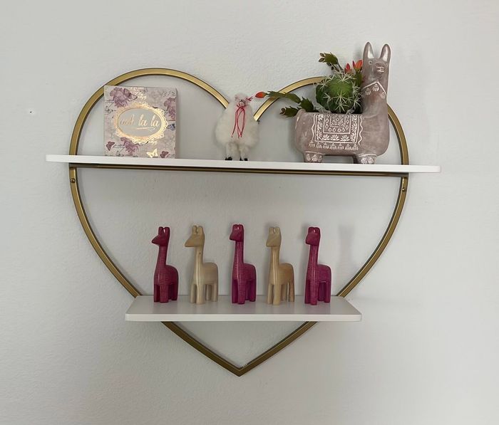 A heart shaped shelf with giraffe figurines on it