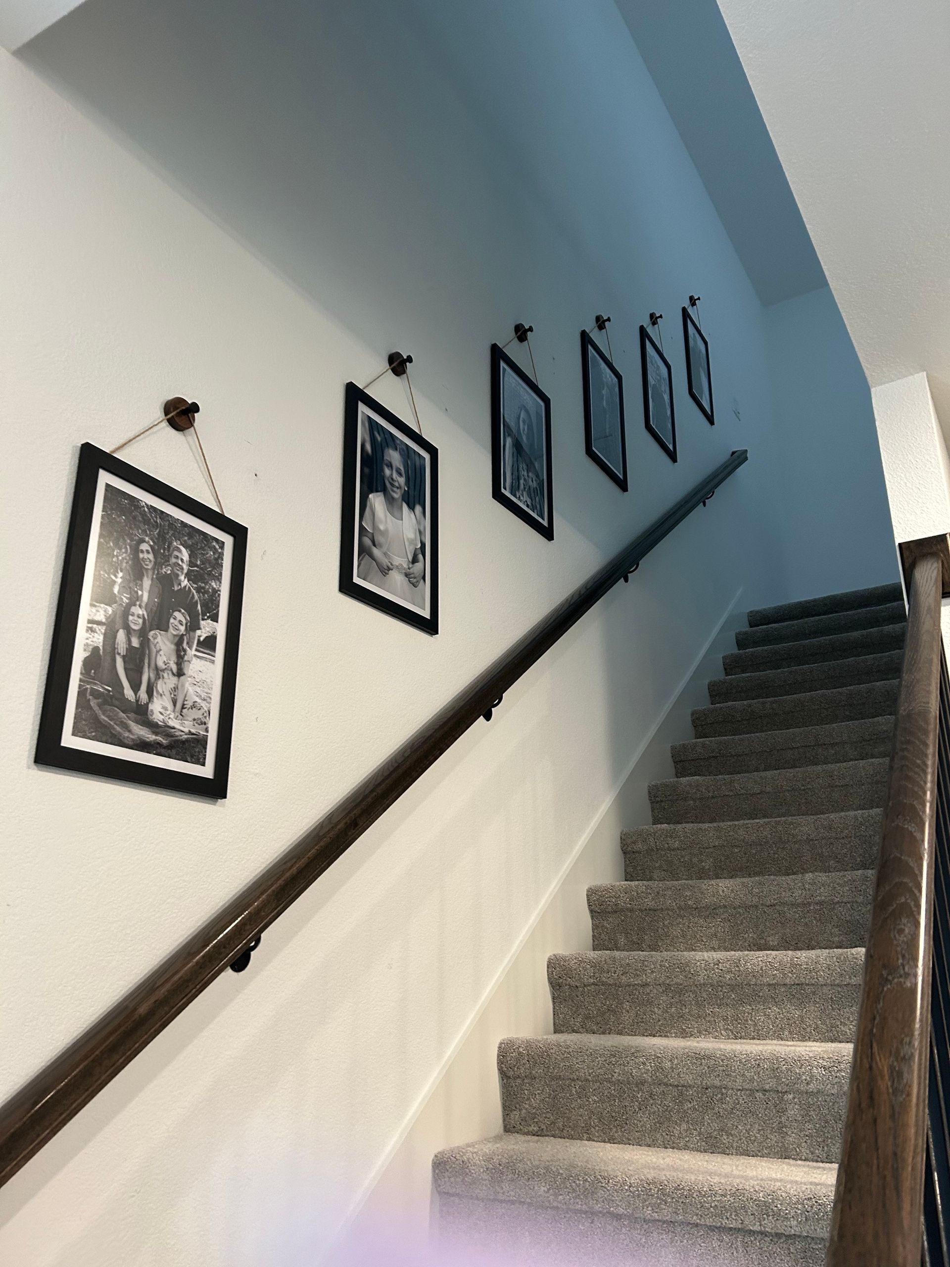 A staircase with a wooden railing and pictures on the wall