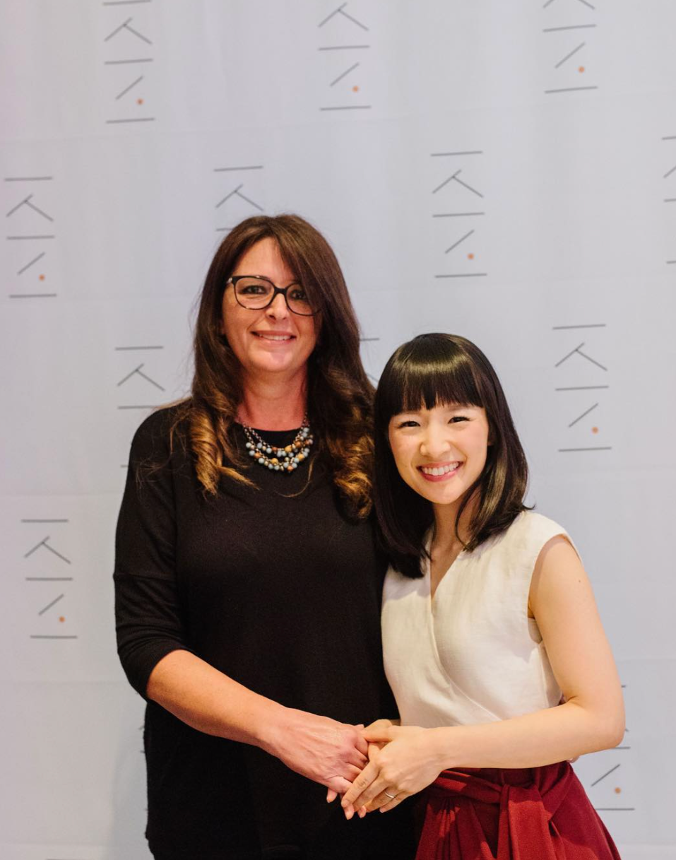 Two women are posing for a picture in front of a wall that says kiki