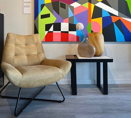 A chair and a table in front of a colorful painting