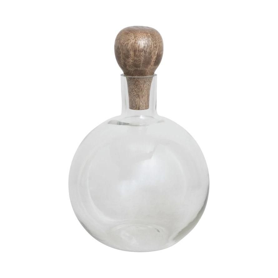 A clear glass bottle with a wooden cork on top.