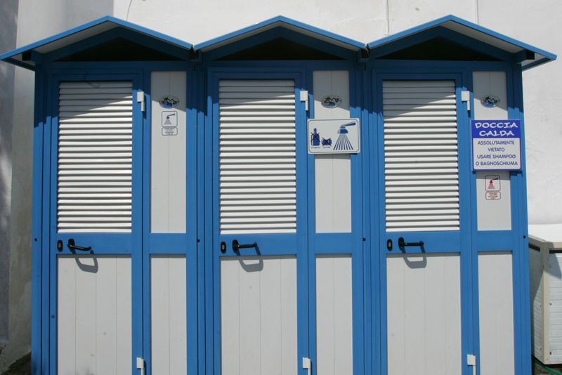 Cabine spogliatoio sulla spiaggia, di colore blu e bianco, con persiane chiuse e piccoli cartelli sulla facciata.