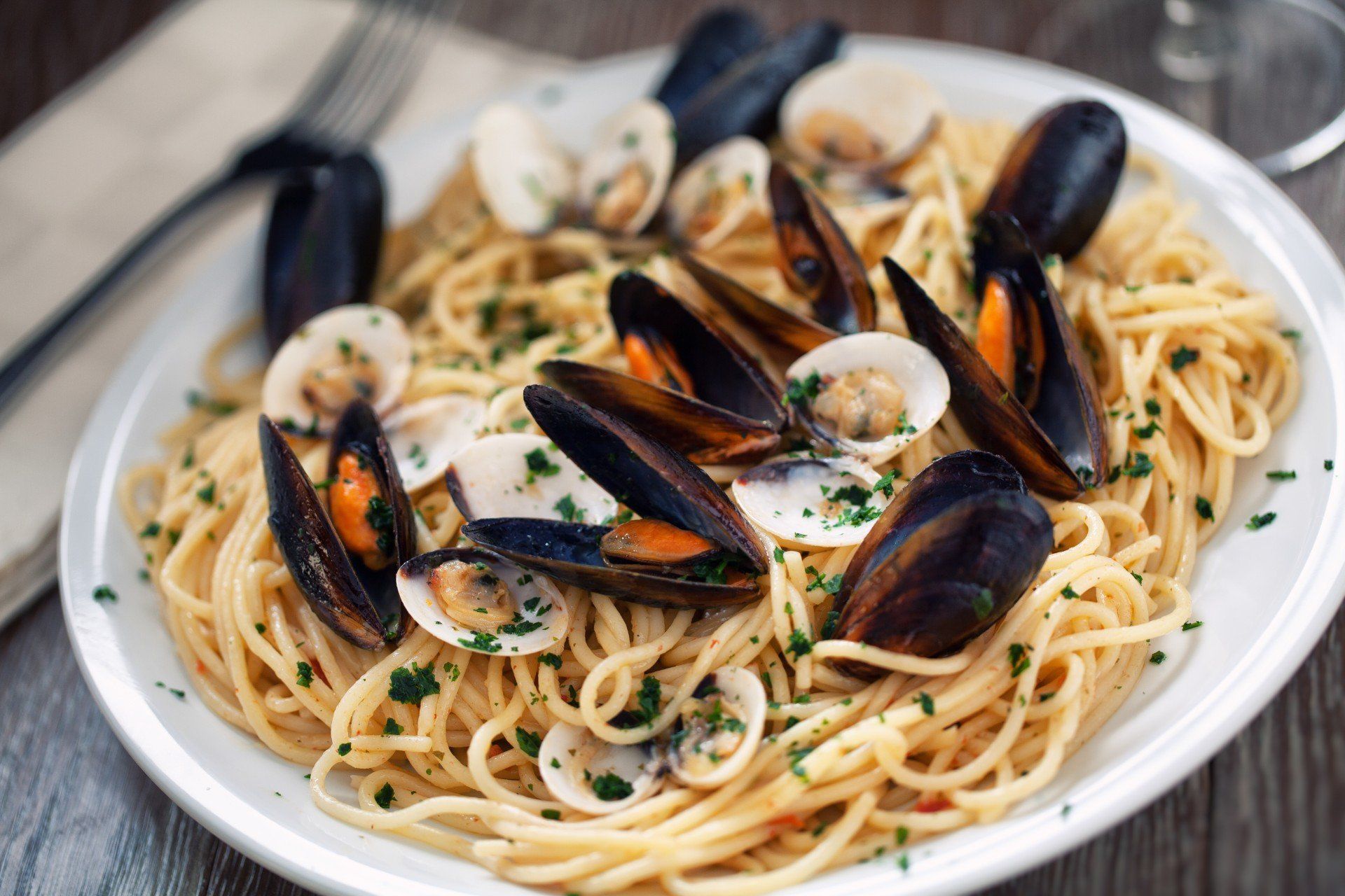 Piatto di spaghetti con cozze e prezzemolo su un piatto bianco
