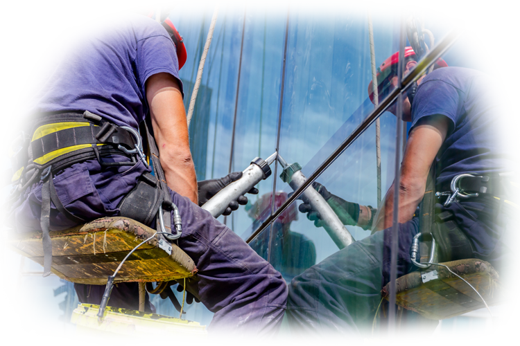 A worker in a safety harness and helmet hangs suspended from a tall building, arms outstretched above city traffic.