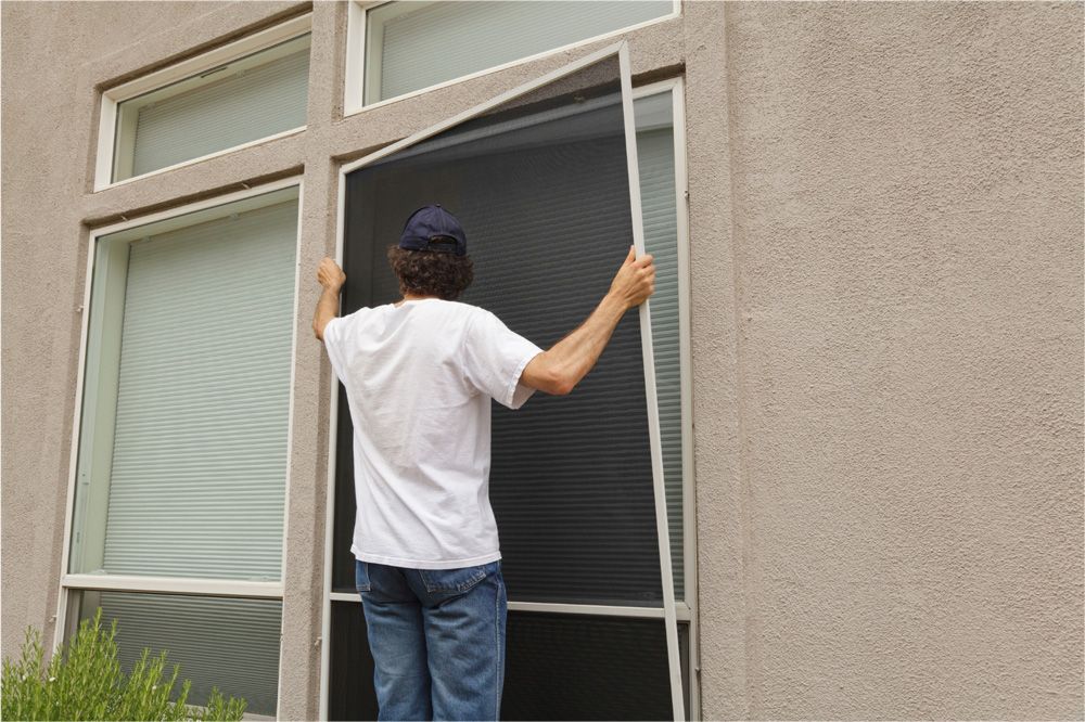 Person installing a window screen on a building.