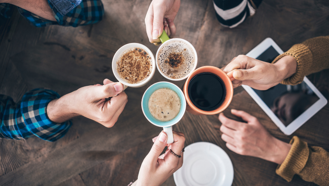 A group of people are sitting at a table drinking coffee.