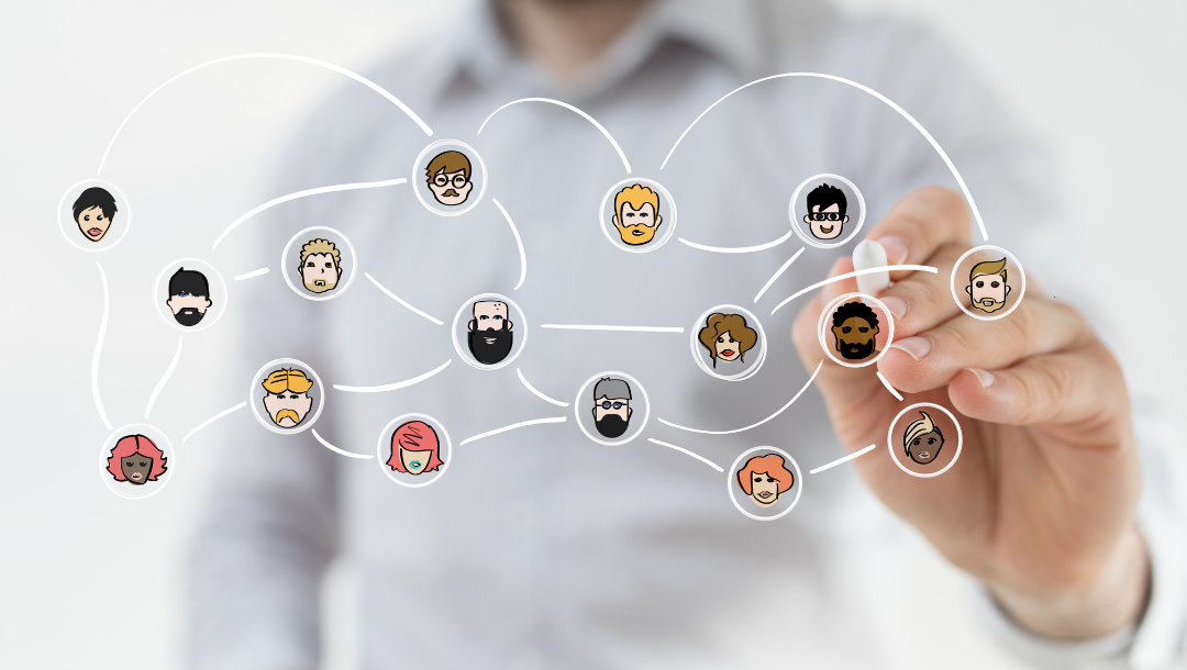 A group of people are sitting around a table with laptops.