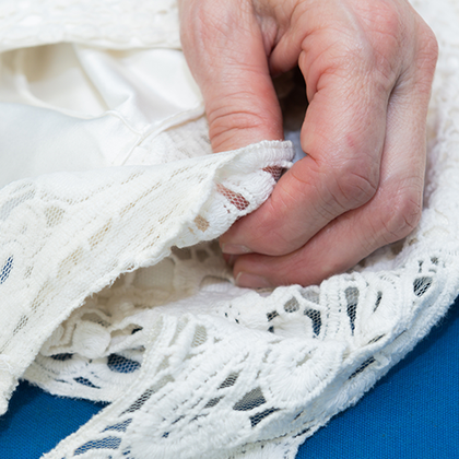 Woman's Hands Holding a White Wedding Dress — Spring Hill, FL — Imperial Dry Cleaners