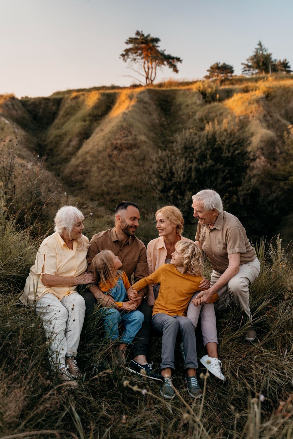 Family sitting on a grassy hillside, smiling.