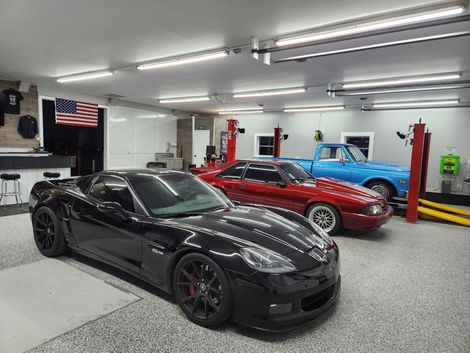 A Black Sports Car Is Parked in a Garage Next to a Red Sports Car and a Blue Truck | Independence Automotive Maintenance & Repair