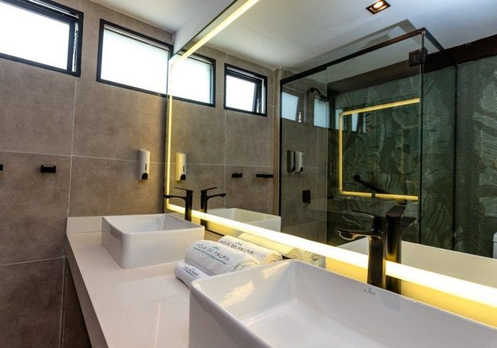 Baño moderno con dos lavabos, gran espejo y ducha de cristal.