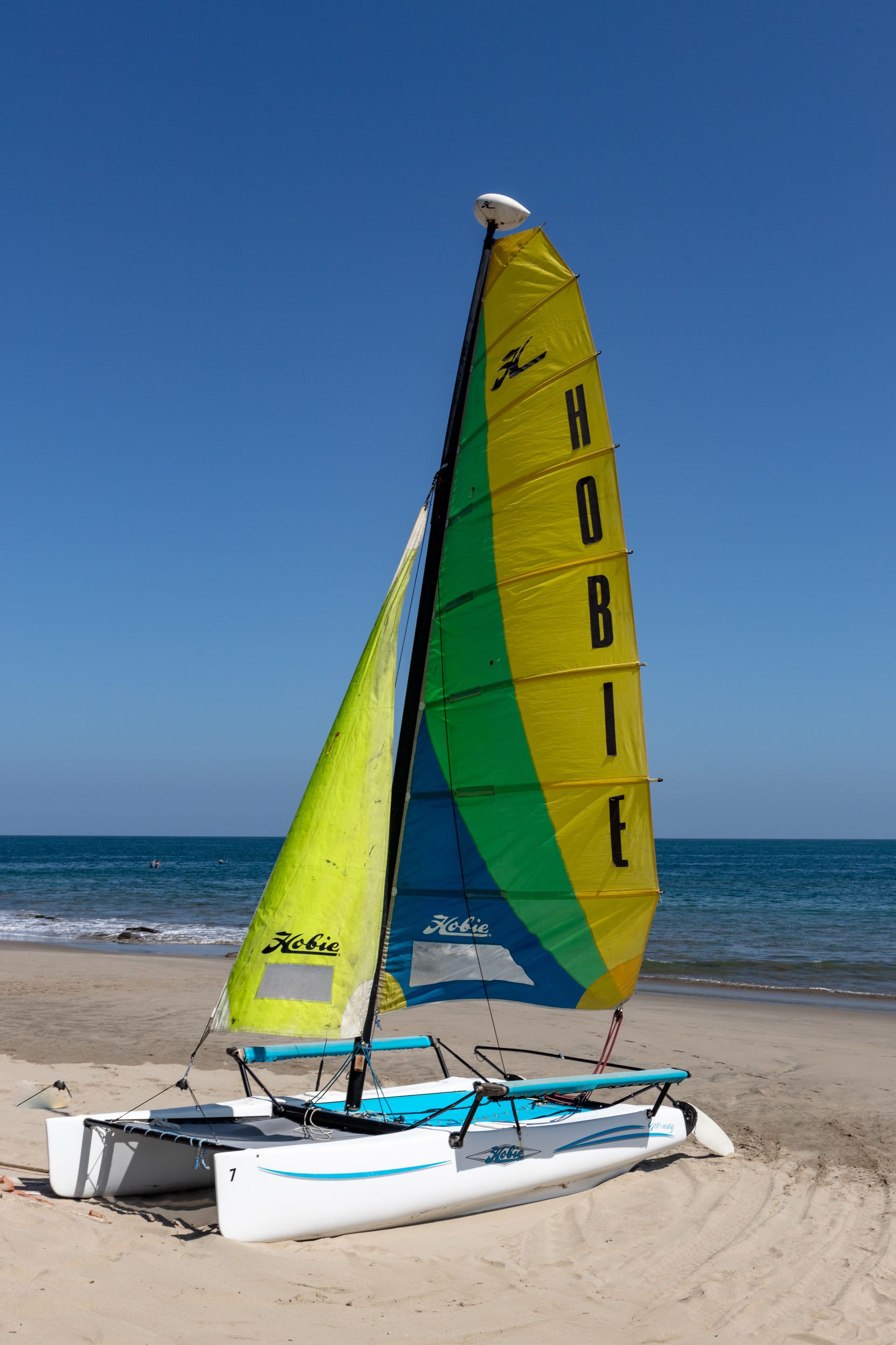 Velero amarillo en tranquilas aguas turquesas con un cielo colorido al atardecer.