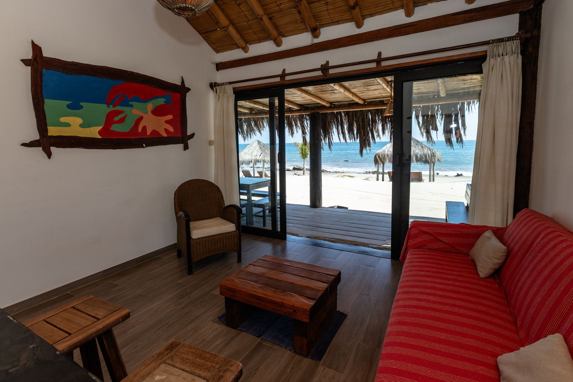 Literas de madera en una habitación con paredes blancas, ventanas sencillas y techo de bambú.