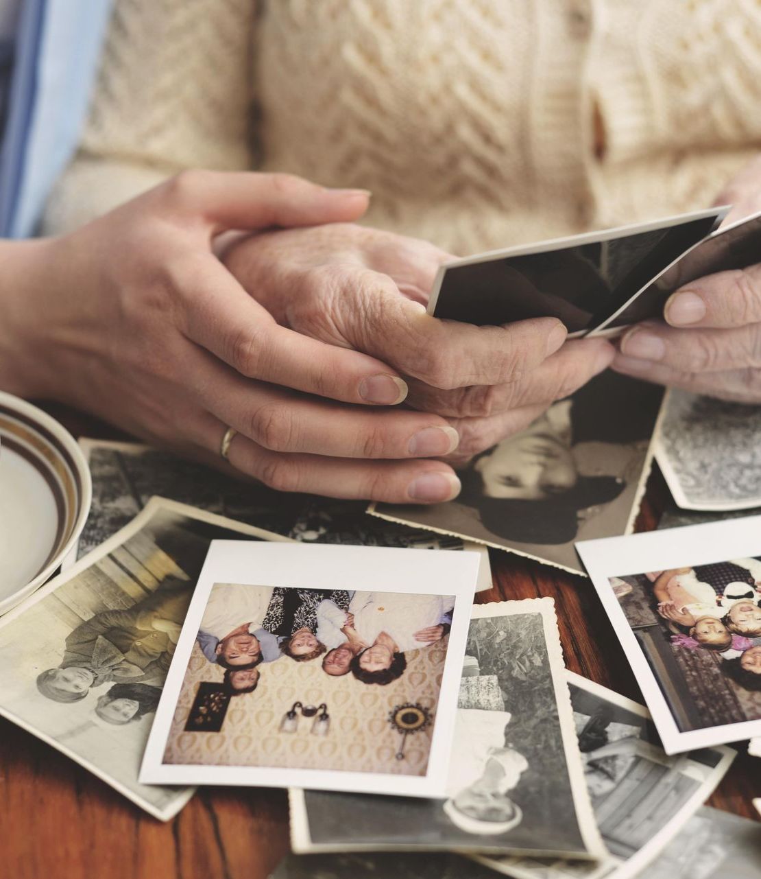 A woman is looking at a pile of old photographs