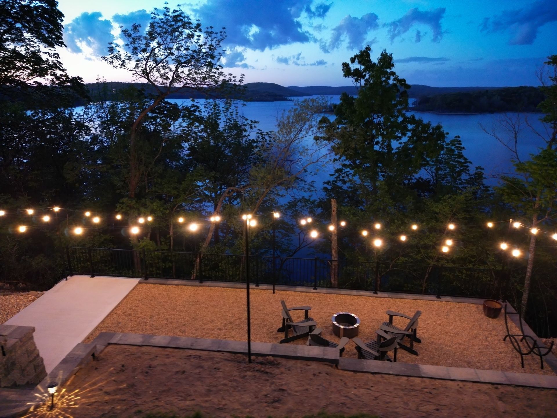 A view of a lake with a fire pit and chairs