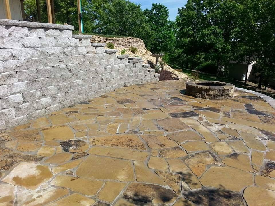 A stone patio with a fire pit in the middle of it.